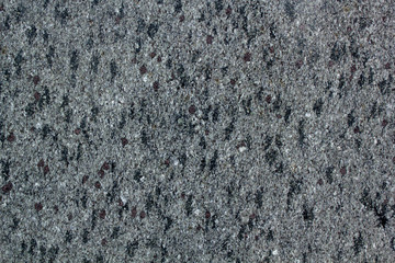 The texture of solid granite tiles. Hard and slippery gray granite surface with a dark spots texture