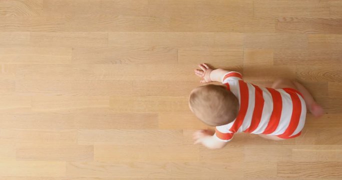 Baby crawling for the first time at home, top view