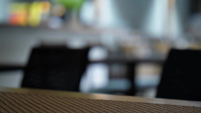 Wet glass of cold white wine stand on table, woman take it to drink. Night time, closeup shot, blurred background