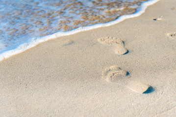 footprint on sand beach with sea wave