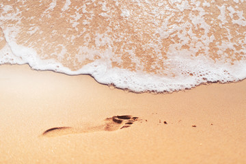 Foot print on sand beach with smooth wave abstract texture background.