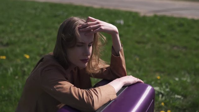 Sad traveler missed her flight and bus - Sitting on her luggage suitcase and crying - Emotions of a white caucasian female woman with light long hair wearng bra and beige jacket