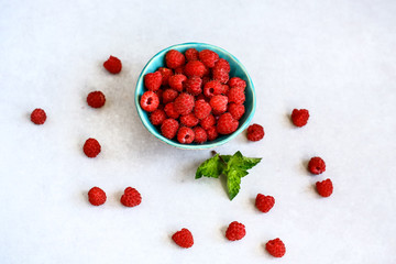 Red fresh raspberries on gray background. Bowl with natural ripe organic berries, top view with copy space