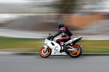 Riding a motorcycle, a man speeds on the track.