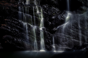 Multiple waterfall streams with silk effect on black stone.