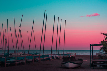 Barcos varados y un chiringuito en la playa durante el atardecer rosa