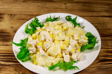 Festive salad with chicken breast, sweet corn, canned pineapple and mayonnaise on wooden table