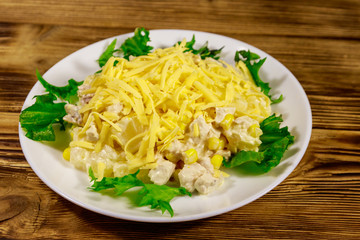 Festive salad with chicken breast, sweet corn, canned pineapple, cheese and mayonnaise on wooden table