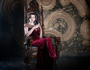 Queen in red dress sitting on throne. Symbol of power © Elina Leonova