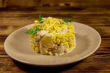 Festive salad with chicken breast, sweet corn, canned pineapple, cheese and mayonnaise on wooden table