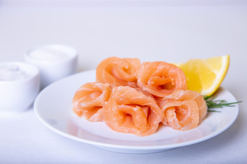 Salted salmon on a white plate with lemon and dill. White background, selective focus, close-up.