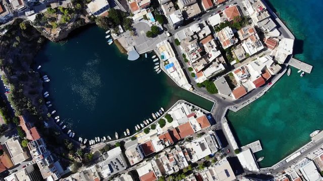 Top view of Voulismeni lake, unique rounded lagoon at coastal town, landmark of Agios Nikolaos city, North-East Crete island area. Small channel connect lake with sea, dense build urban territory