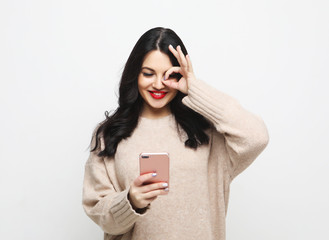 Naklejka premium Fashion curvy brunette girl taking photo makes self portrait on smartphone