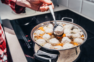 Girl farmer in a plaid shirt mixes up the soup in a saucepan