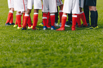Obraz premium Junior Soccer Team Standing in Group. Football Grass Field and Players Feet. Soccer Stadium Grass Background. Soccer Field at School. Young Soccer Players Training on Pitch.