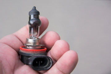 close-up of a faulty fog light bulb in the hands. swollen lamp