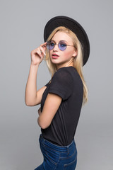 Fototapeta premium Fashion portrait pretty sweet young woman wearing a black hat sunglasses over grey background