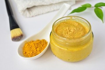 Turmeric face mask in small jar, acne skin treatment, natural cosmetics.