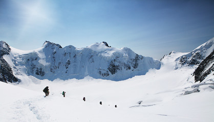 Fototapeta na wymiar A group of mountaineers climbs to the top of a snow-capped mountain. Climbers are hiking on mountain peaks ridge. , Beautiful mountaineering tourism trekking. Concept of Motivation, Teamwork