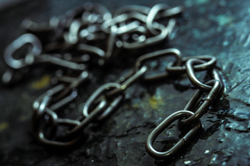 Broken iron chain on dark stone background