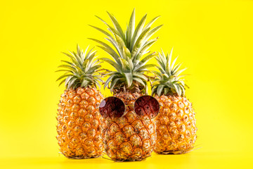 Creative pineapple looking up with sunglasses and shell isolated on yellow background, summer vacation beach idea design pattern, copy space close up