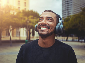 Cheerful man enjoying music on wireless headphone - obrazy, fototapety, plakaty