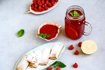 Raspberry jam in a glass jar and cookies on gray table. Healthy breakfast concept. Bio healthy food. Organic fruit jam