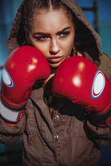 Portrait of female boxer in sport wear with fighting stance against spotlight. Sexy fitness blonde...