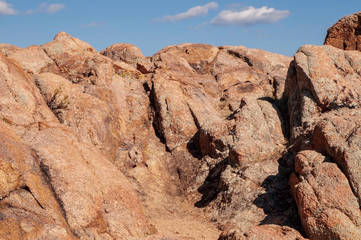 A rock face in the Arizona desert with white clouds and blue skies