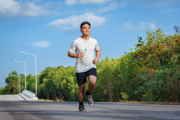Young man jogger athlete training and doing workout outdoors on street  road