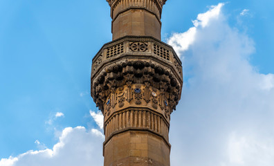 Fantastic detailed minaret against a bright cloudy blue sky on a sunny day.