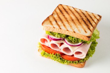 Close-up photo of a club sandwich. Sandwich with meat, prosciutto, salami, salad, vegetables, lettuce, tomato, onion and mustard on a fresh sliced rye bread on wooden background. Olives background.