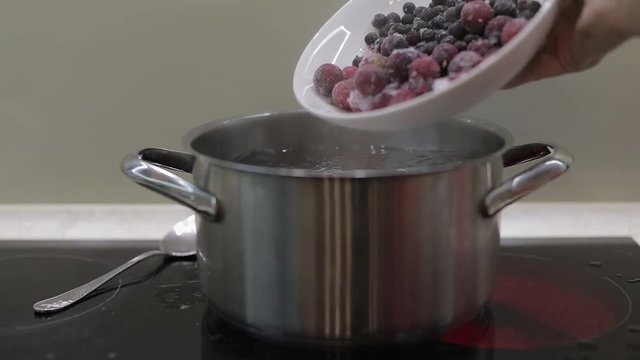 Add the wrozen berries in boiling water. Cooking compote. Kitchen. Slow motion