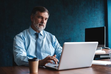 Senior man in office working on laptop computer