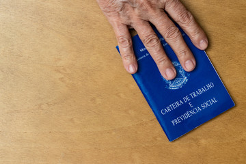 hands of Caucasian senior woman holding work book, Brazilian social security document