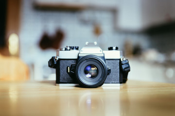 Retro vintage photography camera on a wooden table, blurry background