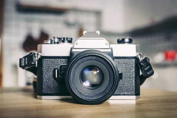 Retro vintage photography camera on a wooden table, blurry background