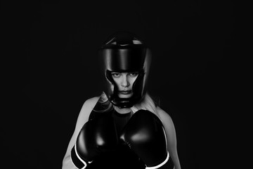 Fototapeta na wymiar Portrait of young woman in boxing gloves and protective helmet on black background. black and white photo