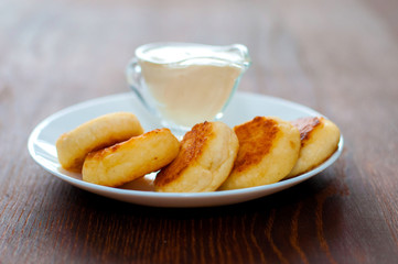 Fried cheese pancakes with sour cream close-up side view. For cafe or restaurant menu design.