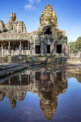 Fototapeta na wymiar Relections of the towers and beautiful face sculptures at the famous Bayon temple in the Angkor Thom temple complex, Siem Reap, Cambodia