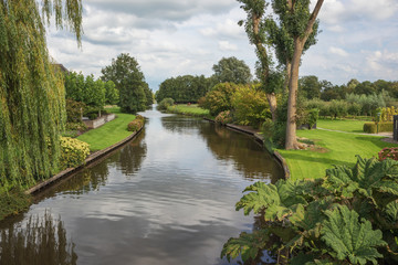 Fototapeta premium Walking over a canal bordered with gardens in Giethoorn