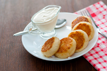 Fried cheese pancakes with sour cream on a white plate view from the top. Can be used for menu design.