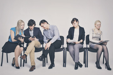 business people waiting in queue sitting in row holding smartphones and cvs, human resources, employment and hiring concept