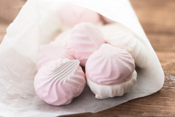 delicious dessert,delicate white and pink marshmallow in white paper on wooden background,