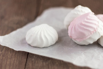 Fototapeta na wymiar delicious dessert, delicate white and pink marshmallow on white paper on wooden background,
