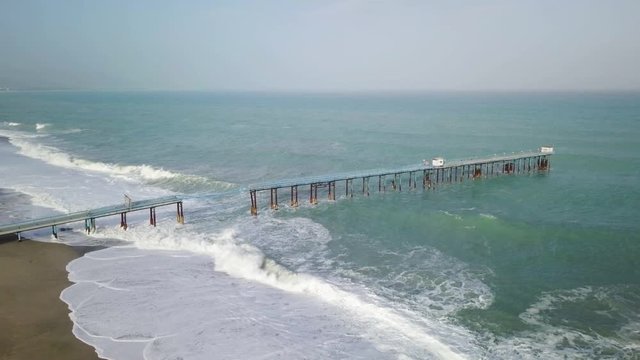 Pontile industriale sull' Oceano distrutto e crollato dalle onde tempestose.