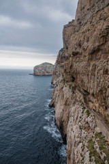 Fototapeta premium Capo Caccia, a rocky outcrop set in a protected ecosystem near the town of Alghero, Sardinia, Italy. featuring. Scenic hiking routes, diving sites & caverns with archaeological remains