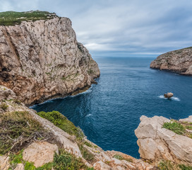 Fototapeta premium Capo Caccia, a rocky outcrop set in a protected ecosystem near the town of Alghero, Sardinia, Italy. featuring. Scenic hiking routes, diving sites & caverns with archaeological remains