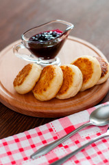 Cheese pancakes with jam, on a wooden platform, with a kitchen towel view from the top, vertical photo