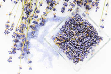 Spa and wellness setting with lavender flowers, sea salt, oil in a bottle, aroma candle on wooden white background